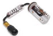 GE sensor pigtail: black cylindrical plug with amber sleeve, wire bundle through light rectangular block, and silver open housing with circular flange and brown gasket
